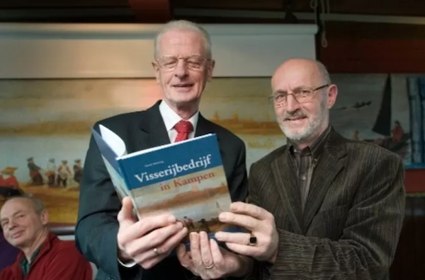 Een trotse Henk Woning houdt oud-burgemeester Kleemans zijn boek Visserijbedrijf in Kampen voor. Foto FREDDY SCHINKEL